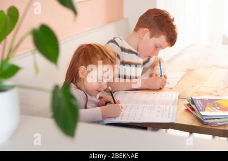 Vor-Teenager-Jungen und Mädchen (Bruder und Schwester) l Schwerpunkt auf ihre Schularbeit während der Heimschulung aufgrund der Coronavirus-Sperre Stockfoto