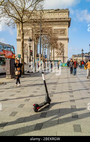 Ein gemieteten Elektroroller links in der Mitte des Bürgersteiges vor dem Arc de Triomphe, auf der Champs-Élysées, Paris, Frankreich. Februar 2020. Stockfoto