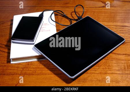 Tablet mit Powerbank auf einem Nachttisch Stockfoto