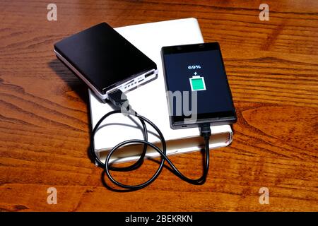 Smartphone im Laden mit einer Powerbank auf einem Buch und einem Destkop Stockfoto
