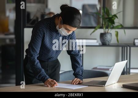 Weibliche Angestellte in Gesichtsmaske Arbeit im Büro Stockfoto