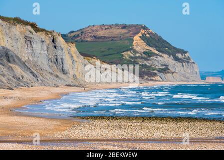 Charmouth, Dorset, Großbritannien. April 2020. Wetter in Großbritannien. Blick entlang des fast menschenleeren Strandes von Charmouth in Dorset an einem warmen sonnigen Nachmittag mit Blick auf Golden Cap an der Jurassic Coast während der Coronavirus Pandemie Sperrung. Bild: Graham Hunt/Alamy Live News Stockfoto