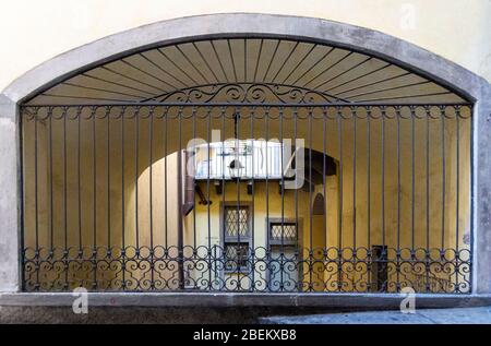 Blick auf einen Innenhof durch einen verzierten Eisengitter in der Altstadt von Burgamo, Italien Stockfoto