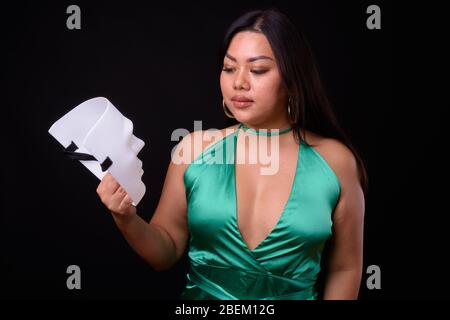 Schöne übergewichtige asiatische Frau trägt seidig grünes Kleid Stockfoto