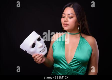 Schöne übergewichtige asiatische Frau trägt seidig grünes Kleid Stockfoto