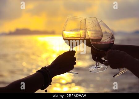 Nahaufnahme der Hände mit Rotweinglas auf dem Balkon bei Sonnenuntergang, Konzept der Feier Stockfoto