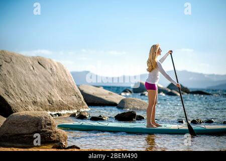 Aktive junge Frau paddeln über einen See Stockfoto