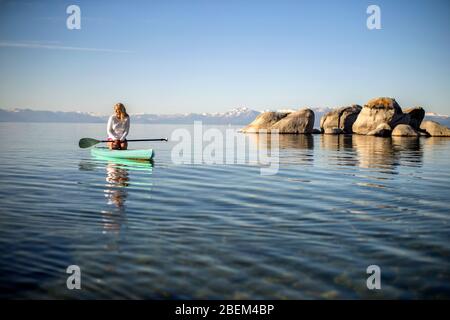 Junge Frau paddeln über einen See Stockfoto