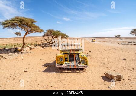 Gelbes, zerstörtes Auto, das in der Wüste Sahara in Marokko, Afrika, aufgegeben wurde Stockfoto