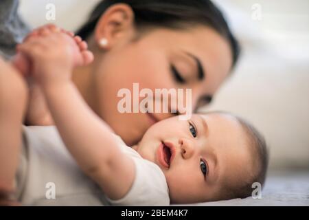 Porträt eines kleinen Mädchens, das mit ihrer Mutter auf einem Bett liegt Stockfoto