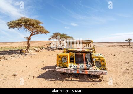 Gelbes, zerstörtes Auto, das in der Wüste Sahara in Marokko, Afrika, aufgegeben wurde Stockfoto