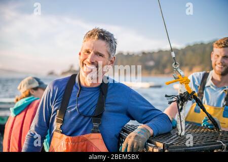 Porträt des reifen Mannes auf seinem Fischerboot mit Familiencrew Stockfoto