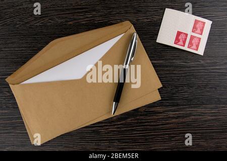 Brauner Umschlag, Stift und Stempel auf dunklem Holztisch Stockfoto