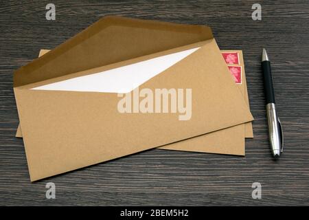 Brauner Umschlag, Stift und Stempel auf dunklem Holztisch Stockfoto