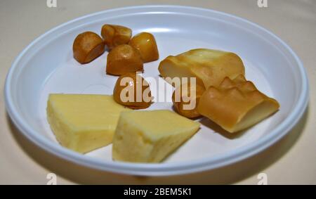 Auswahl an polnischem Käse auf weißem Teller: Tilsit oder Tylżycki, Gołka oder Gouka und Oscypek Käse in Scheiben geschnitten und bereit für eine Käseverkostung. Smokey che Stockfoto