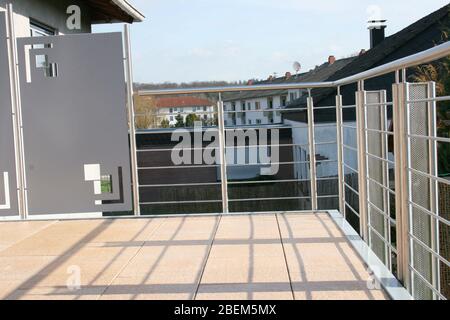 Eine Terrasse mit Edelstahlgeländer und beigefarbenen Bodenfliesen eine Terrasse mit Edelstahlgeländer und beigen Bodenplatten Stockfoto