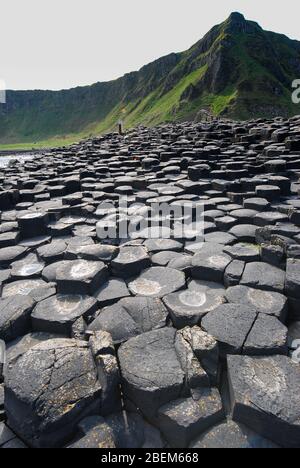 Ein Pfad aus Steinen mit einem Berg im Hintergrund am Giant's Causeway, Antrim Coast, Nordirland, Großbritannien Stockfoto