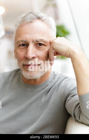 Bild eines schönen reifen älteren grauhaarigen bärtigen Geschäftsmann sitzen im Café. Stockfoto