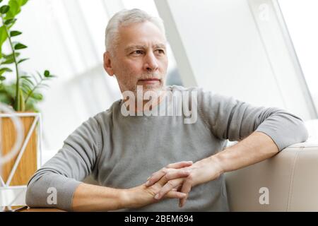 Bild eines älteren grauhaarigen bärtigen Geschäftsmannes sitzen im Café. Stockfoto