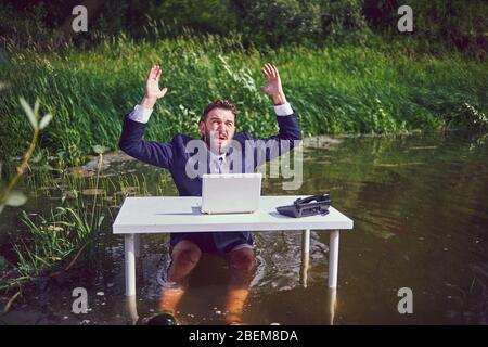 Frustriert, deprimiert Mann mit Kopf in den Händen von Konkurs Lager untergang am Schreibtisch mit Laptop geschockt, gestresst müde Geschäftsmann fühlt Stockfoto