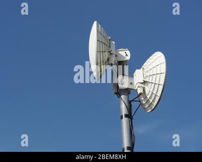 Antennen/Router des ländlichen Breitband-Wireless-Internetdienstes. Schalen für Backhaul zu Masten auf dem Netzwerk-Backbone, aufrechte Antennen für lokale Räumlichkeiten. Stockfoto