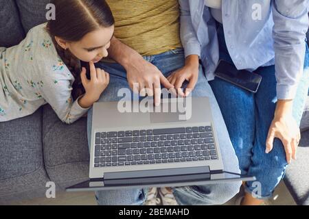Nahaufnahme von oben, wenn eine glückliche Familie zuhause mit einem Laptop sitzt. Stockfoto