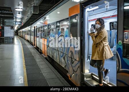 Eine Frau, die als vorbeugende Maßnahme eine Sanitärmaske trägt und den Zug am ersten Arbeitstag für nicht-essentielle Bereiche verlässt.Trotz der Tatsache, dass die Haft andauert, In Katalonien sind in der ersten Phase, in der nach dem Notstandsbeschluss die industrielle Tätigkeit wieder aufgenommen wurde, rund 900,000 Beschäftigte wieder in ihren Arbeitsplatz zurückgekehrt. Barcelona steht wegen der Ansteckung von Covid-19 vor seiner 31. Haushaft. Stockfoto