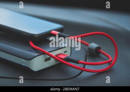 Aufladen des Smartphones mit einem tragbaren Ladegerät - Powerbank. Das Konzept der modernen Autonomie mobiler Geräte. Stockfoto