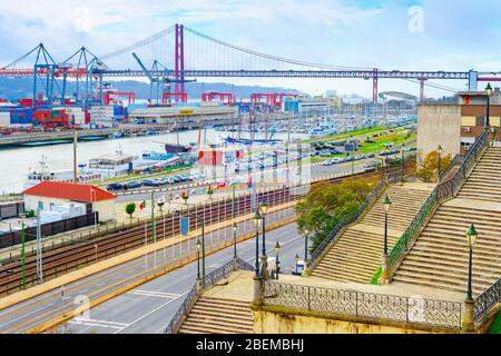 Gepflasterte Treppen zum Handelshafen von Lissabon am Tejo, Schiffe, Kräne, Container, Brücke am 25. April im Hintergrund, Stockfoto