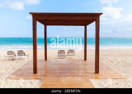 Leerer Holzpavillon und Sonnenliegen sind am Sandstrand an sonnigen Tagen, Dominikanische Republik Stockfoto