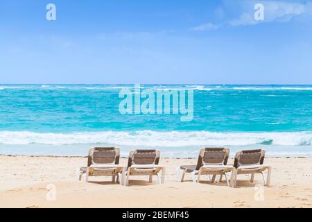 Liegestühle sind am Sandstrand bei schönem Tag, Dominikanische Republik Stockfoto