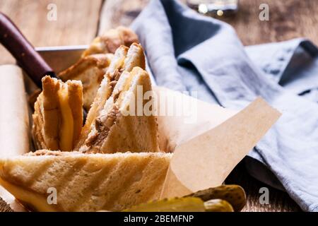 Hausgemachte Thunfisch-Sandwiches mit Käse serviert mit Gurken auf rustikalem Holztisch Stockfoto