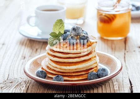 Gesundes vegetarisches Frühstück oder Brunch, Lieblingsgericht. Hausgemachte Pfannkuchen, frische Sommerbeeren, Kaffee und Saft auf Holztisch Stockfoto