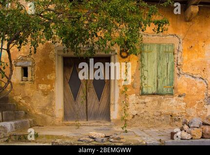 Eine alte Holztür und Fensterläden in einem verödeten Gebäude im historischen Bergdorf Stanjel in der Gemeinde Komen in Primorska, Süd-w Stockfoto