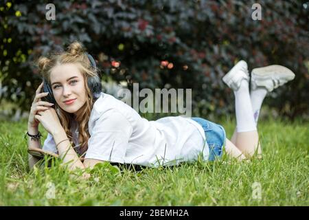 Junge Mädchen Teenager hört das Radio mit Kopfhörern. Auf dem Gras liegen. Konzept für Lifestyle, Hobby, Musik und Freizeit. Stockfoto