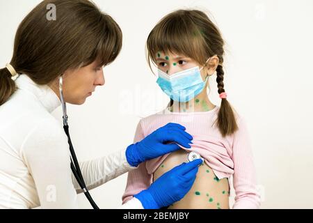 Arzt untersucht Mädchen mit grünen Ausschlägen auf Gesicht und Bauch erkrankt an Windpocken, Masern oder Röteln Virus. Stockfoto