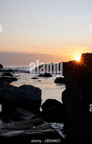 Panorama-Shot Silhouette der Meer Stack Felsformationen bei einem goldenen Sonnenuntergang mit natürlichen Sonnenstrahlen und Reflexionen Stockfoto