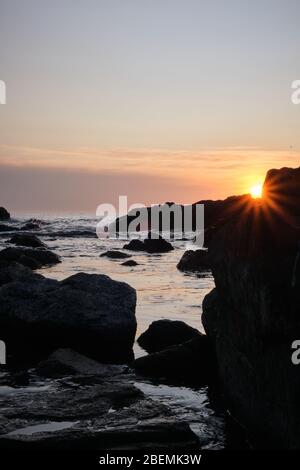 Panorama-Shot Silhouette der Meer Stack Felsformationen bei einem goldenen Sonnenuntergang mit natürlichen Sonnenstrahlen und Reflexionen Stockfoto