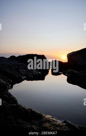 Panorama-Shot Silhouette der Meer Stack Felsformationen bei einem goldenen Sonnenuntergang mit natürlichen Sonnenstrahlen und Reflexionen Stockfoto