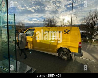 München, Deutschland - 2. Februar 2020: Deutsche Frau beim gelben Volkskwagen Deutche Post DHL Postverteilwagen Stockfoto