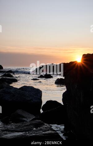 Panorama-Shot Silhouette der Meer Stack Felsformationen bei einem goldenen Sonnenuntergang mit natürlichen Sonnenstrahlen und Reflexionen Stockfoto