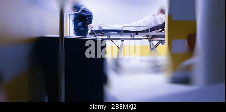 Defokussierte unscharfe konzeptionelle Darstellung eines nicht erkennbaren Patienten auf dem Krankenhauskorridor während der weltweiten Krankheitsinfektion durch das ansteckende Coronavirus Covid-19 Stockfoto