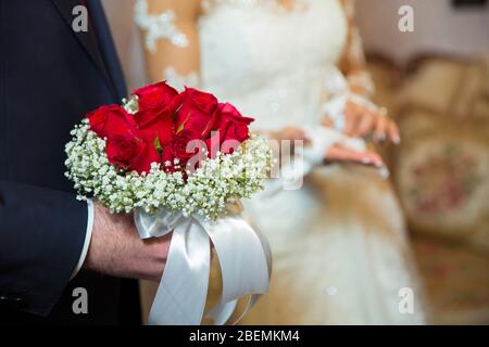 Schöne Braut hält eine Hochzeit roten Strauß. Bräutigam hält Braut roten Strauß Nahaufnahme . Stockfoto