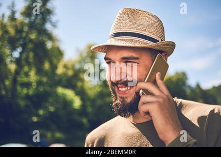 Junger bärtiger Mann mit Smartphone auf einem Hintergrund der Natur Stockfoto