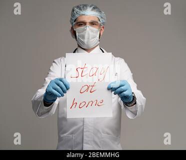 Coronavirus. Arzt hält ein Schild mit der Aufschrift "Stay at Home" globale Botschaft für die Coronavirus-Krise. Quarantäne-Nachricht auf der ganzen Welt, um COVI zu bekämpfen Stockfoto