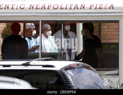 Brooklyn, Usa. April 2020. Beschäftigte des Gesundheitswesens, die Schutzmaske und medizinische Kleidung tragen, stehen am Dienstag, den 14. April 2020, vor dem Eingang des Wyckoff Heights Medical Center in New York City. Bis heute sind fast 285,000 Menschen infiziert und mehr als 14,000 Menschen sind in NY, NJ und CT gestorben. Es gibt jedoch Anzeichen dafür, dass die Kurve abflacht. Foto von John Angelillo/UPI Quelle: UPI/Alamy Live News Stockfoto
