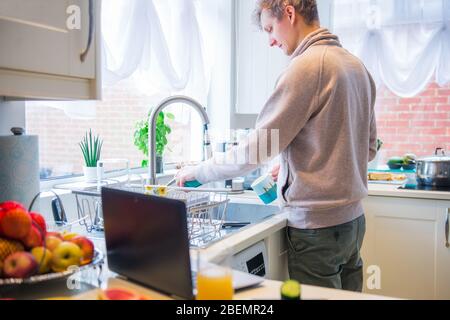 Junger kaukasischer Mann, der von zu Hause aus arbeitet. Freiberufliche Waschküche und Arbeit am pc-Laptop. Home Office, Remote Workplace Konzept. Weich Stockfoto