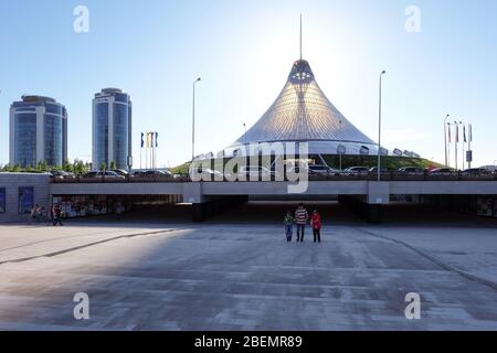 NUR-SULTAN, ASTANA, KASACHSTAN - 3. JUNI 2015: Khan Shatyr Entertainment Center mit herrlichem Sonnenuntergang angenehmes Licht. Mann mit zwei Jungen davor Stockfoto