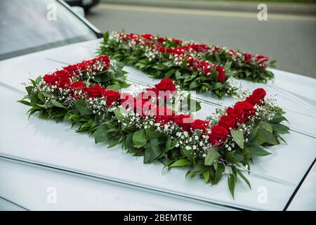 Die Buchstaben E und N auf dem Auto sind aus Blumen. Schöne bunte Hochzeit Blumenstrauß auf weißen Hochzeitsauto. Wunderschönes Hochzeitsauto. Vorderseite des Stockfoto