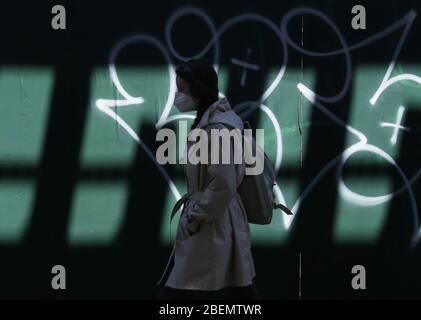 Brooklyn, Usa. April 2020. Ein Fußgänger geht am Dienstag, den 14. April 2020, allein mit einer schützenden Gesichtsmaske auf dem Bürgersteig in New York City. Bis heute sind fast 285,000 Menschen mit dem Coronavirus infiziert und mehr als 14,000 Menschen sind in NY, NJ und CT gestorben. Es gibt jedoch Anzeichen dafür, dass die Kurve abflacht. Foto von John Angelillo/UPI Quelle: UPI/Alamy Live News Stockfoto